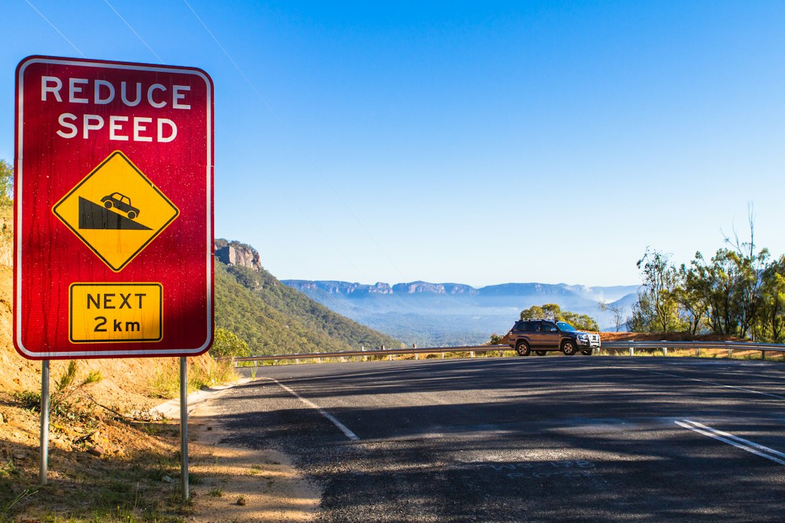 Reduce Speed warning sign above a winding road in the Australian bush