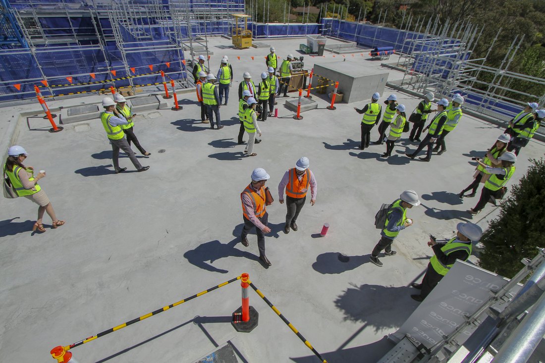 Workers in hard hats and hi-vis vests on a construction deck, viewed from above